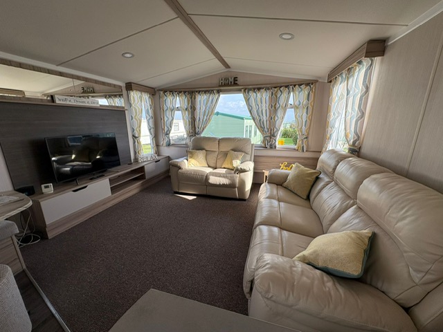Spacious living room with leather seating and panoramic sea views - luxury caravan lounge at Sands of Luce