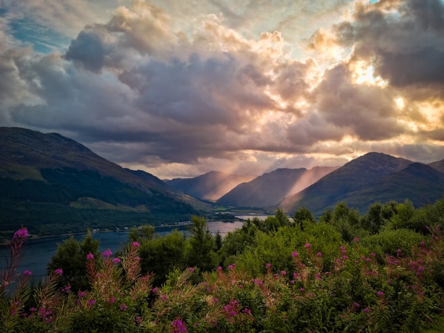 sun shining through clouds over mountains